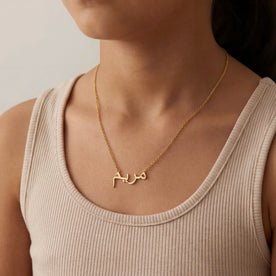 Girl modelling gold kids Arabic name necklace on anchor chain