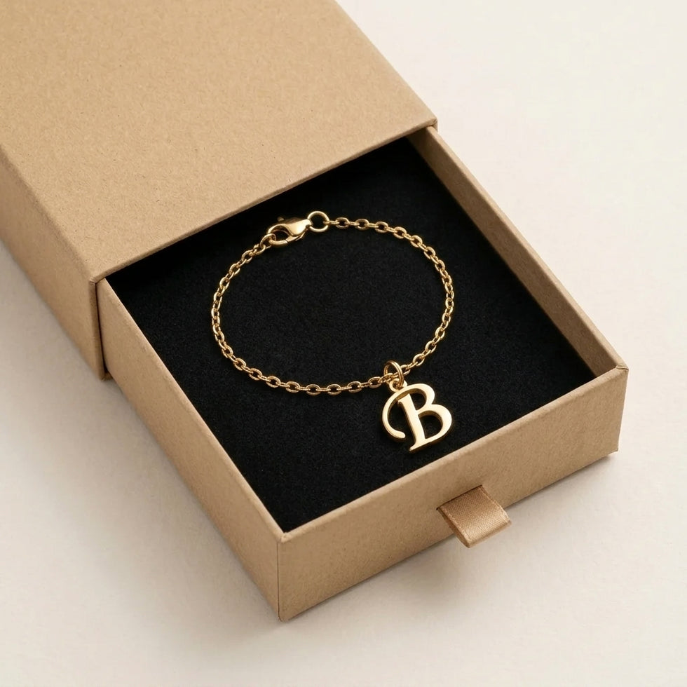 Personalised gold initial bracelet with the letter B in the Mia style, presented in the kraft gift box it is sent in.