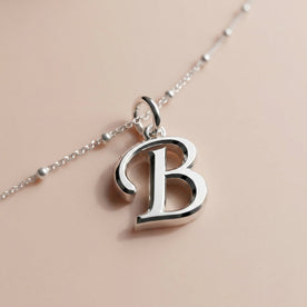 Personalised silver initial bracelet with the letter B in the Zara style, close up, showing the polished cut edge and the thickness of the metal.