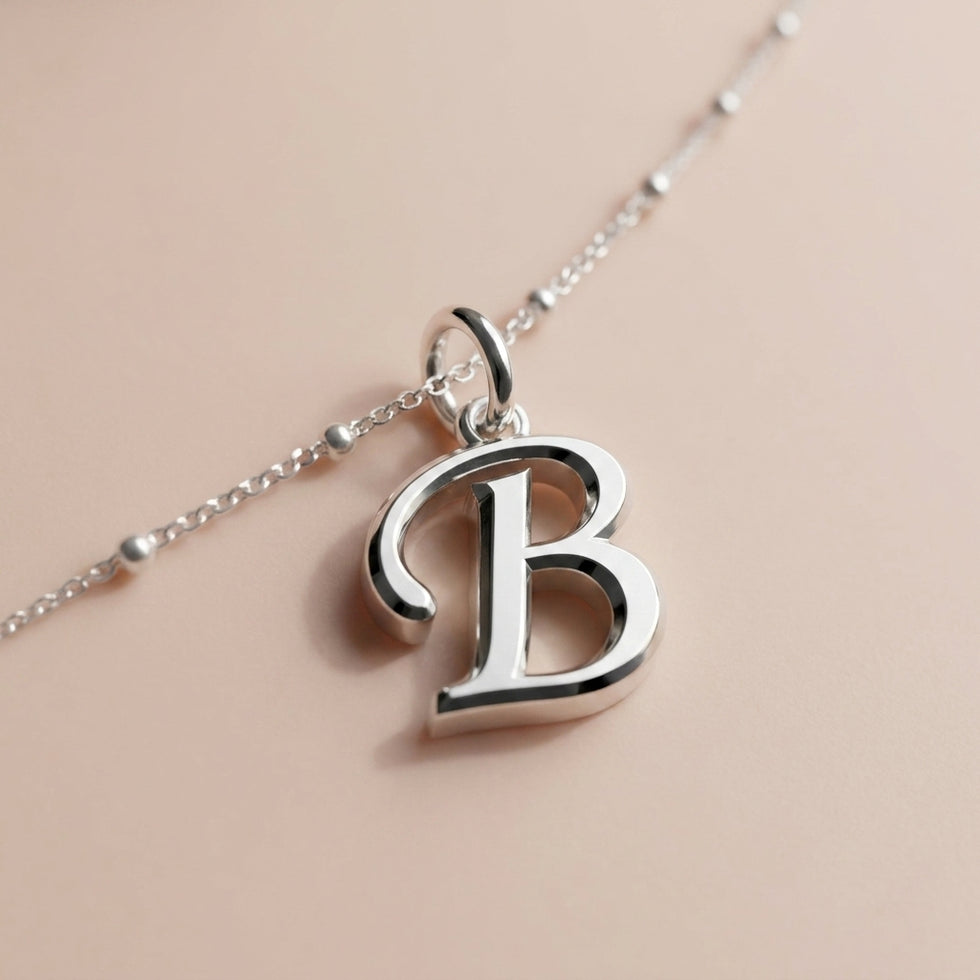 Personalised silver initial bracelet with the letter B in the Zara style, close up, showing the polished cut edge and the thickness of the metal.