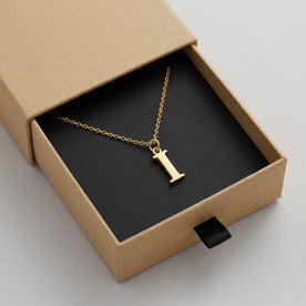 Personalised gold initial necklace with the letter I in the Mia style, presented in the kraft gift box it is sent in.