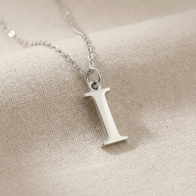 Personalised silver initial necklace with the letter I in the Mia style, close up, showing the polished cut edge and the thickness of the metal.