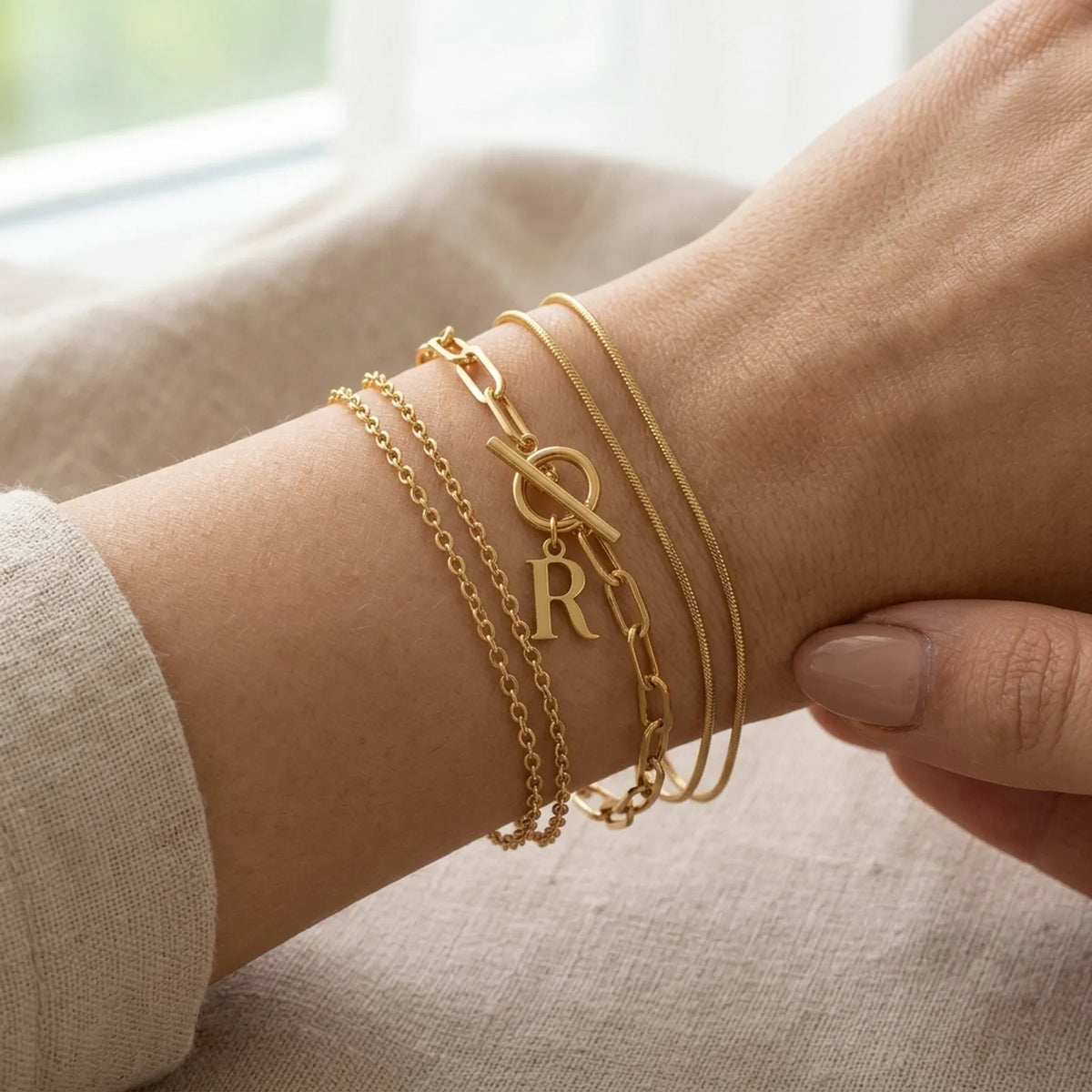 Bracciale con iniziale, catena ovale Belcher a T e ciondoli multipli in oro o argento.