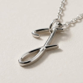 Personalised silver initial necklace with the letter J in the Zara style, close up, showing the polished cut edge and the thickness of the metal.