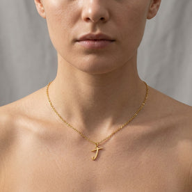 Personalised gold initial necklace with the letter J in the Eva style, worn at the base of the throat.