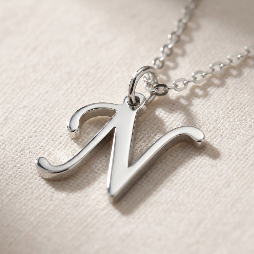 Personalised silver initial necklace with the letter N in the Zara style, close up, showing the polished cut edge and the thickness of the metal.