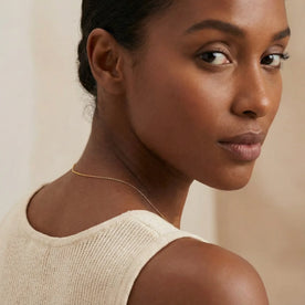 Woman looking over her shoulder wearing a gold anchor chain necklace