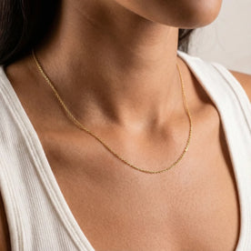 Gold anchor chain necklace worn with a white vest top