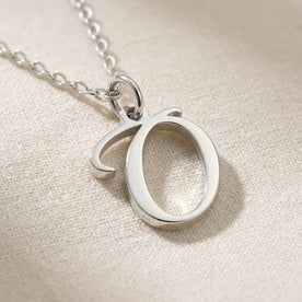 Personalised silver initial necklace with the letter O in the Zara style, close up, showing the polished cut edge and the thickness of the metal.