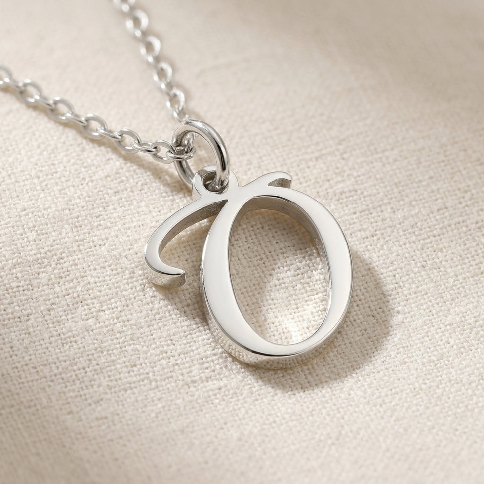 Personalised silver initial necklace with the letter O in the Zara style, close up, showing the polished cut edge and the thickness of the metal.