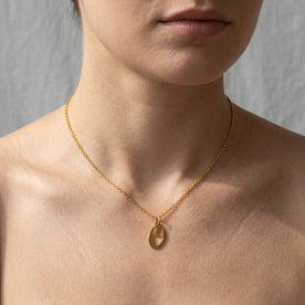 Personalised gold initial necklace with the letter O in the Eva style, worn at the base of the throat.