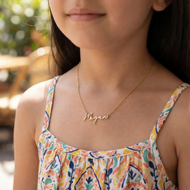 Girl modelling gold kids personalised Megan necklace on an anchor chain - Anna font