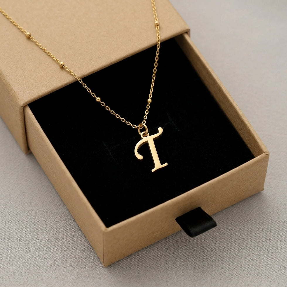 Personalised gold initial necklace with the letter T in the Mia style, presented in the kraft gift box it is sent in.