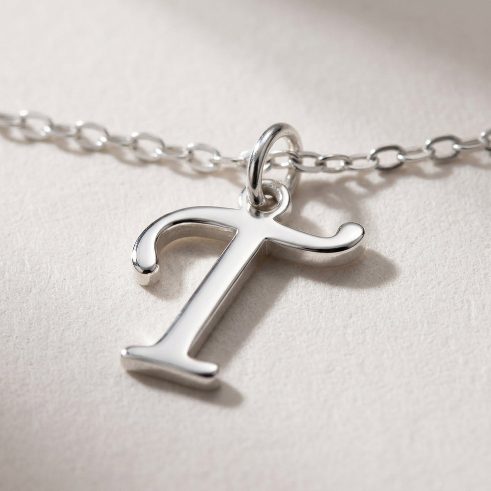 Personalised silver initial necklace with the letter T in the Zara style, close up, showing the polished cut edge and the thickness of the metal.