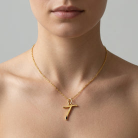 Personalised gold initial necklace with the letter T in the Eva style, worn at the base of the throat.