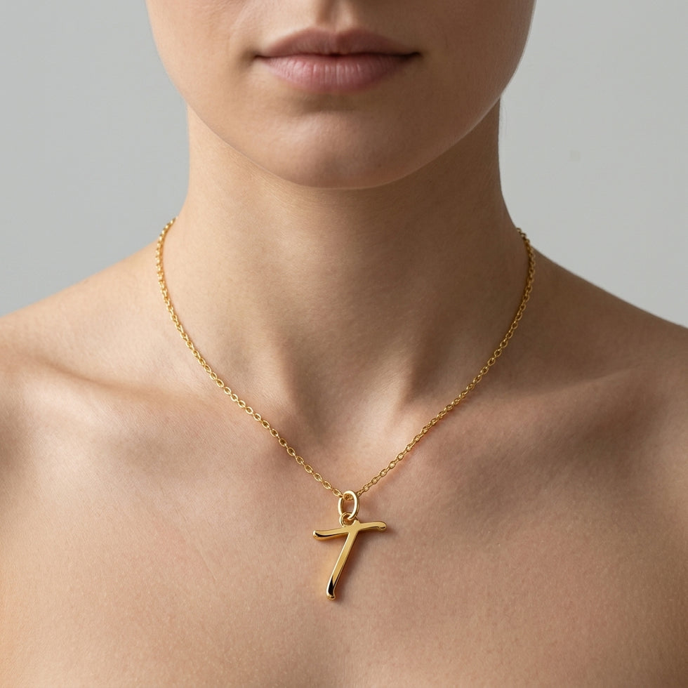Personalised gold initial necklace with the letter T in the Eva style, worn at the base of the throat.