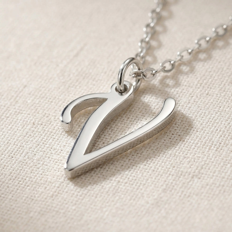 Personalised silver initial necklace with the letter V in the Zara style, close up, showing the polished cut edge and the thickness of the metal.