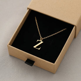 Personalised gold initial necklace with the letter Z in the Mia style, presented in the kraft gift box it is sent in.