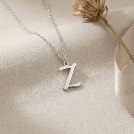 Personalised silver initial necklace with the letter Z in the Bella style, styled on linen with dried flowers.