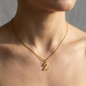 Personalised gold initial necklace with the letter Z in the Eva style, worn at the base of the throat.